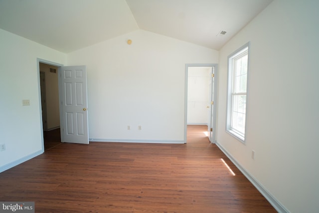 spare room with visible vents, vaulted ceiling, baseboards, and wood finished floors