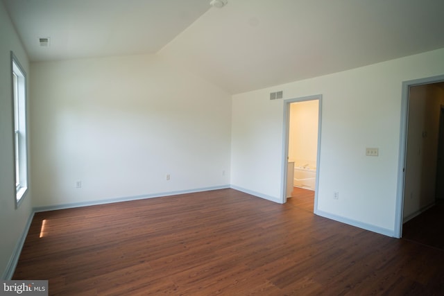 spare room featuring lofted ceiling, dark wood-style flooring, visible vents, and baseboards