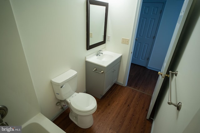 bathroom with toilet, wood finished floors, vanity, and baseboards