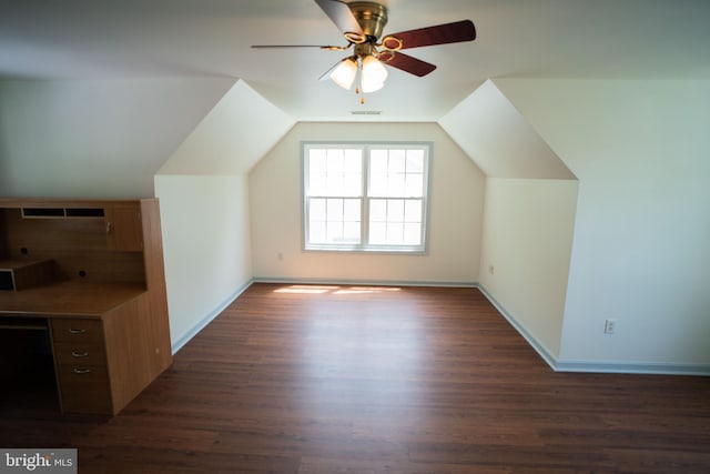 additional living space featuring baseboards, visible vents, dark wood finished floors, a ceiling fan, and vaulted ceiling