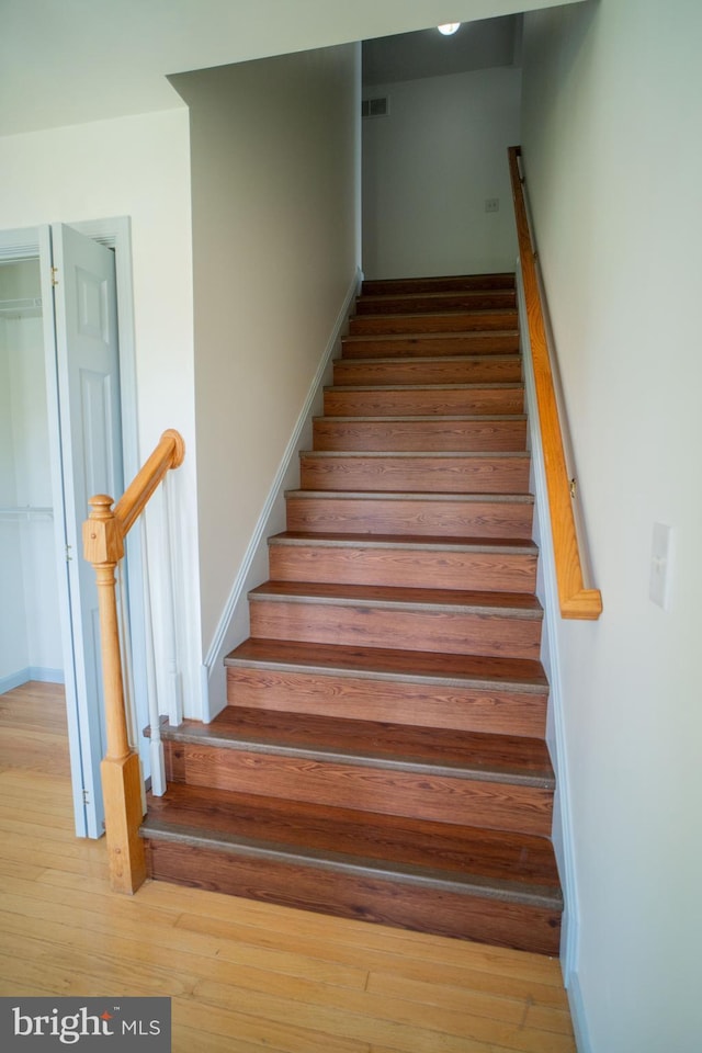 stairs with wood finished floors and visible vents