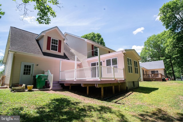 rear view of property with a deck, a yard, and a shingled roof