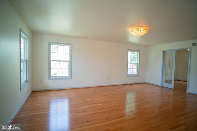 spare room with light wood finished floors, visible vents, and baseboards