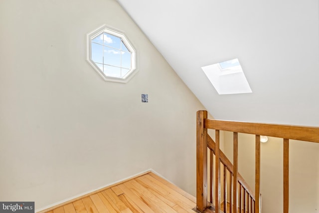 interior space with vaulted ceiling with skylight and wood finished floors