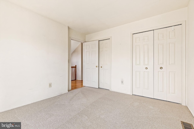 unfurnished bedroom with visible vents, multiple closets, and carpet flooring