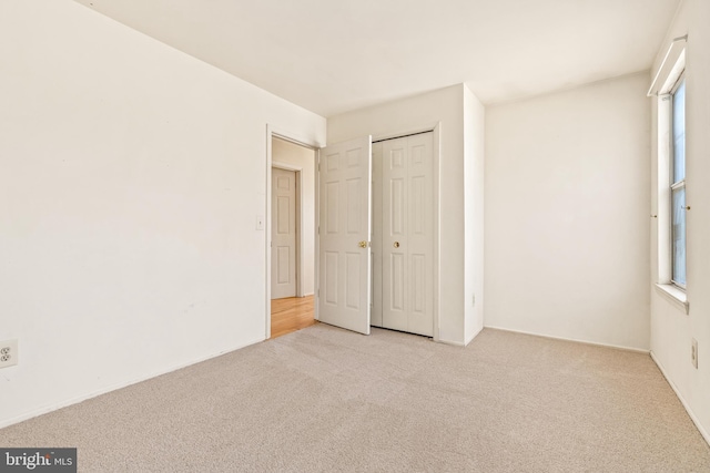 unfurnished bedroom with light carpet and a closet