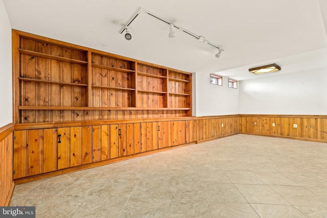 spare room with built in features, a wainscoted wall, and wood walls