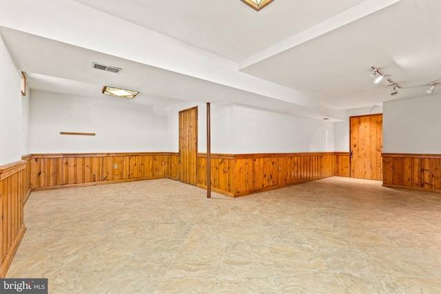 unfurnished room with wainscoting, wood walls, and visible vents