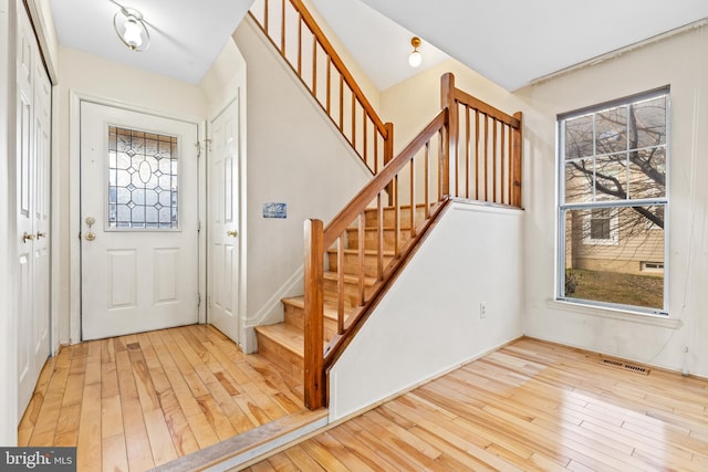 foyer entrance featuring wood-type flooring, visible vents, and stairs