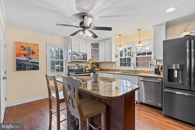 kitchen featuring ornamental molding, stainless steel appliances, a kitchen bar, open shelves, and a sink