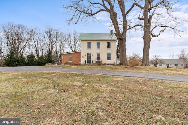 view of front of property featuring a front lawn and metal roof