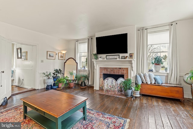 living area featuring hardwood / wood-style flooring, a brick fireplace, and a wealth of natural light