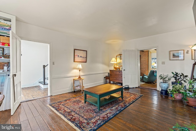 living area featuring stairway, hardwood / wood-style flooring, and baseboards