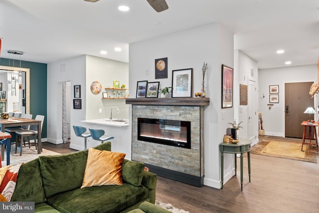 living room featuring baseboards, a fireplace, wood finished floors, and recessed lighting