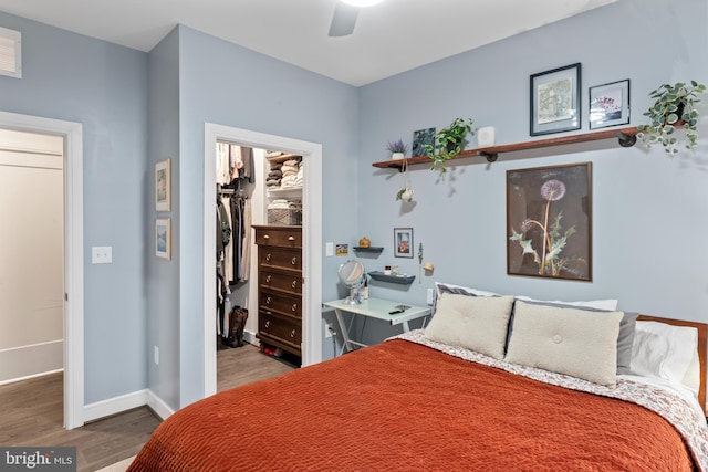 bedroom featuring baseboards, a ceiling fan, wood finished floors, a walk in closet, and a closet