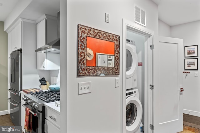 laundry room with laundry area, stacked washer and dryer, visible vents, and baseboards