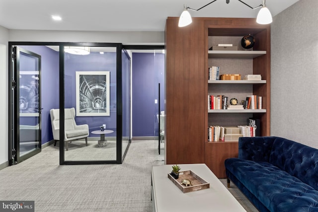 interior space with carpet floors, built in shelves, and baseboards