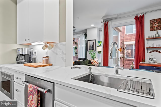 kitchen with white cabinets, light stone countertops, stainless steel dishwasher, a sink, and recessed lighting