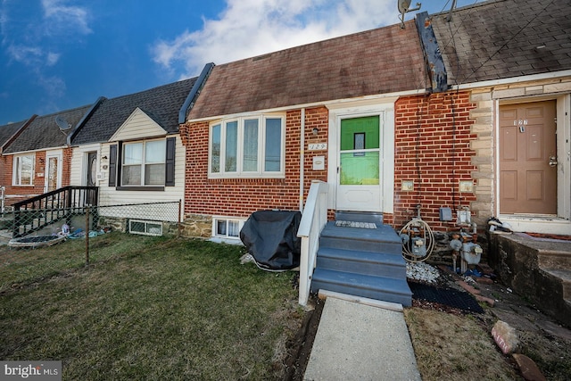 view of front of property with brick siding, a front yard, and a shingled roof