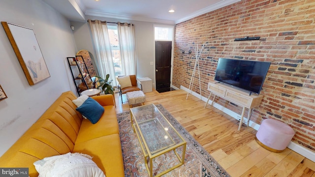 living room with brick wall, ornamental molding, wood finished floors, and baseboards