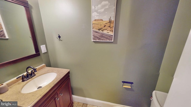 half bath with toilet, baseboards, and vanity