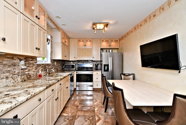 kitchen featuring marble finish floor, appliances with stainless steel finishes, glass insert cabinets, and decorative backsplash