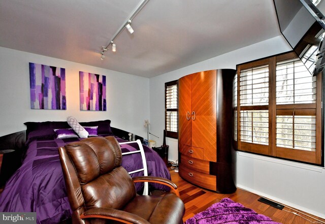 bedroom with visible vents, track lighting, and wood finished floors