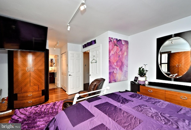 bedroom with rail lighting and wood finished floors