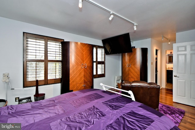 bedroom with wood finished floors and rail lighting