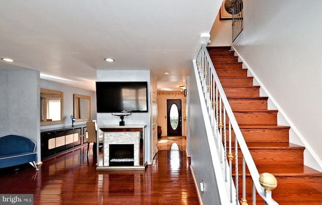 stairs with baseboards, a stone fireplace, wood finished floors, and recessed lighting