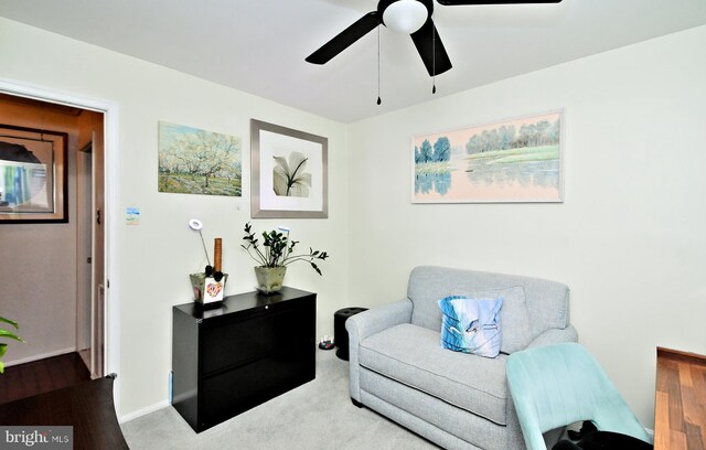 living area with carpet, baseboards, and a ceiling fan