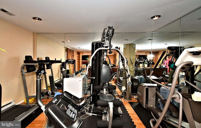 gym with a baseboard heating unit, visible vents, and wood finished floors