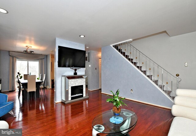 living area featuring stairs, a fireplace, wood finished floors, and recessed lighting