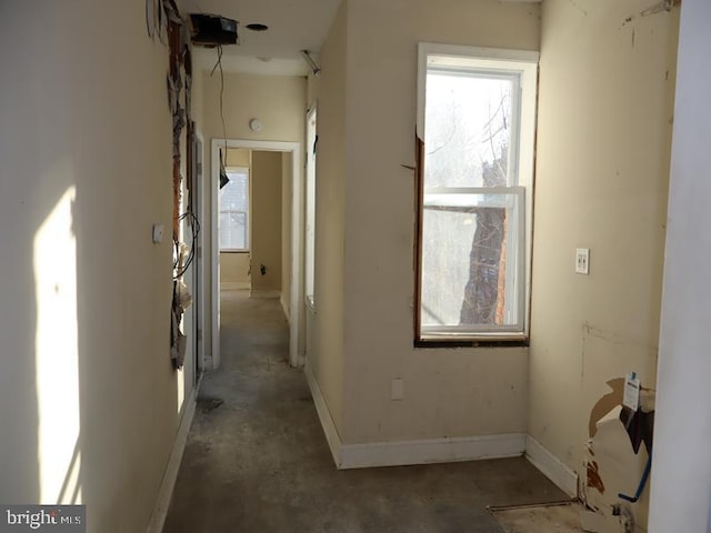 hallway with baseboards and unfinished concrete floors