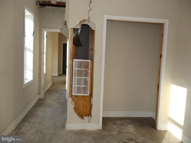 hallway featuring concrete flooring and baseboards