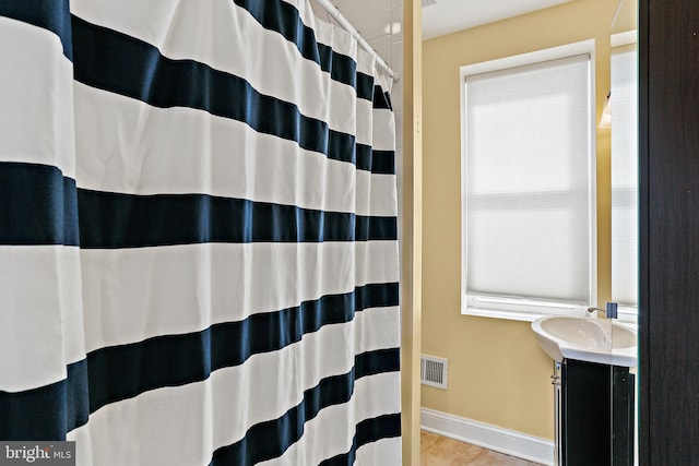 bathroom featuring curtained shower, visible vents, vanity, baseboards, and tile patterned floors