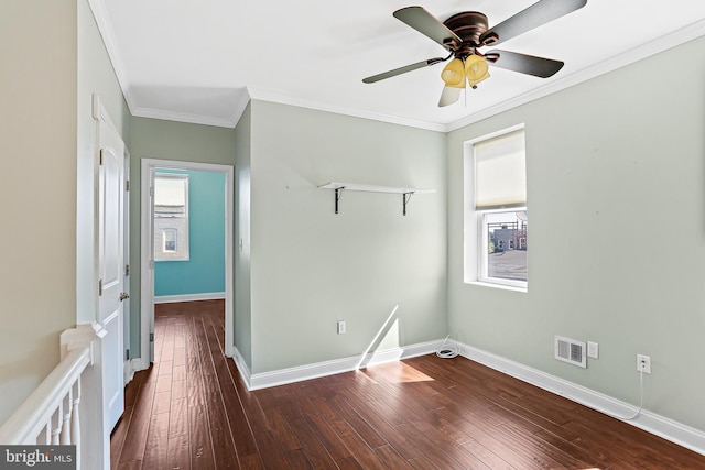 empty room with dark wood-style floors, visible vents, ornamental molding, and baseboards