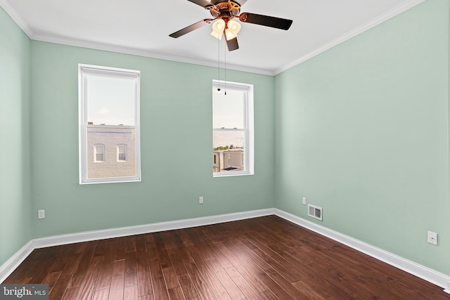 spare room with dark wood-style flooring, visible vents, crown molding, and baseboards