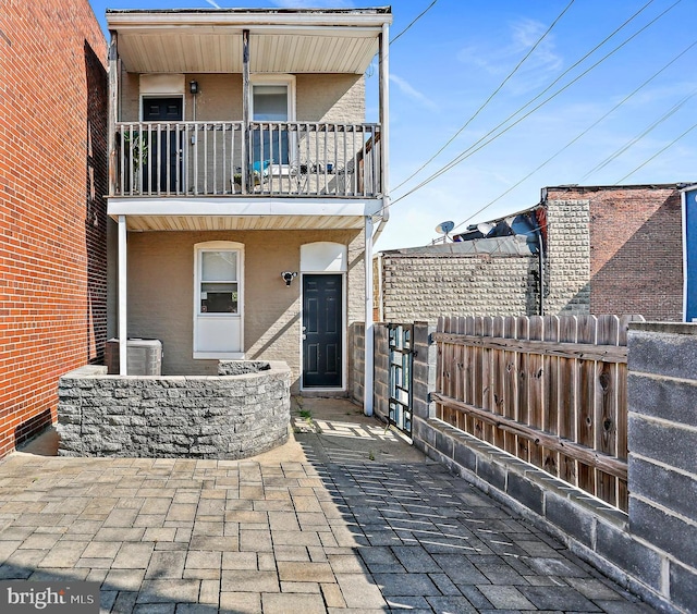 exterior space featuring central air condition unit, fence, a balcony, and stucco siding