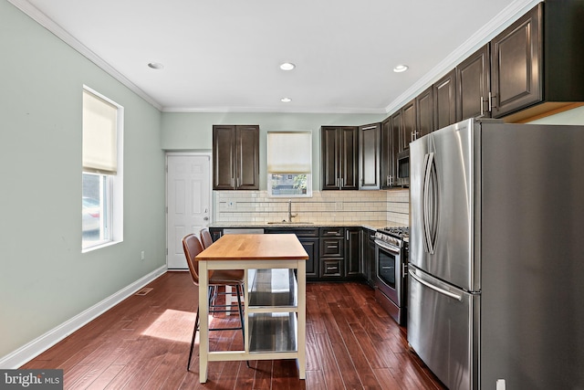 kitchen featuring dark brown cabinets, appliances with stainless steel finishes, backsplash, and a sink