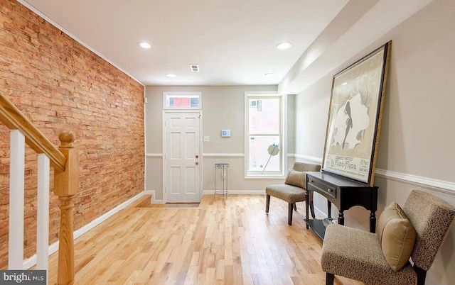 entrance foyer featuring recessed lighting, stairway, brick wall, light wood-type flooring, and baseboards