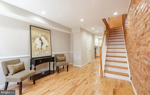 sitting room with recessed lighting, wood finished floors, visible vents, baseboards, and stairs