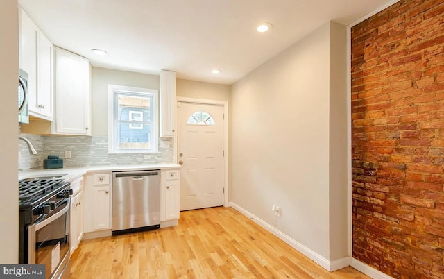 kitchen with tasteful backsplash, baseboards, appliances with stainless steel finishes, light countertops, and white cabinetry