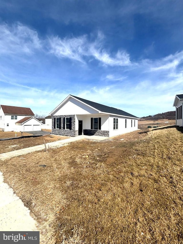 back of property with stone siding and a yard