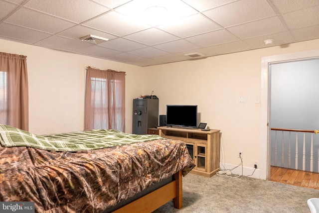 carpeted bedroom with a paneled ceiling, visible vents, and baseboards