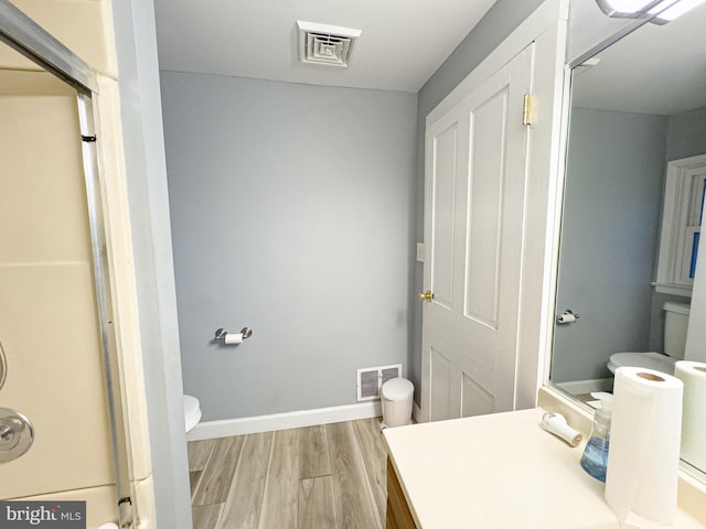 bathroom with toilet, wood finished floors, visible vents, and baseboards