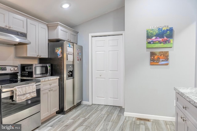 kitchen featuring lofted ceiling, under cabinet range hood, visible vents, appliances with stainless steel finishes, and wood tiled floor