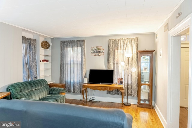 living area featuring ornamental molding, baseboards, and wood finished floors