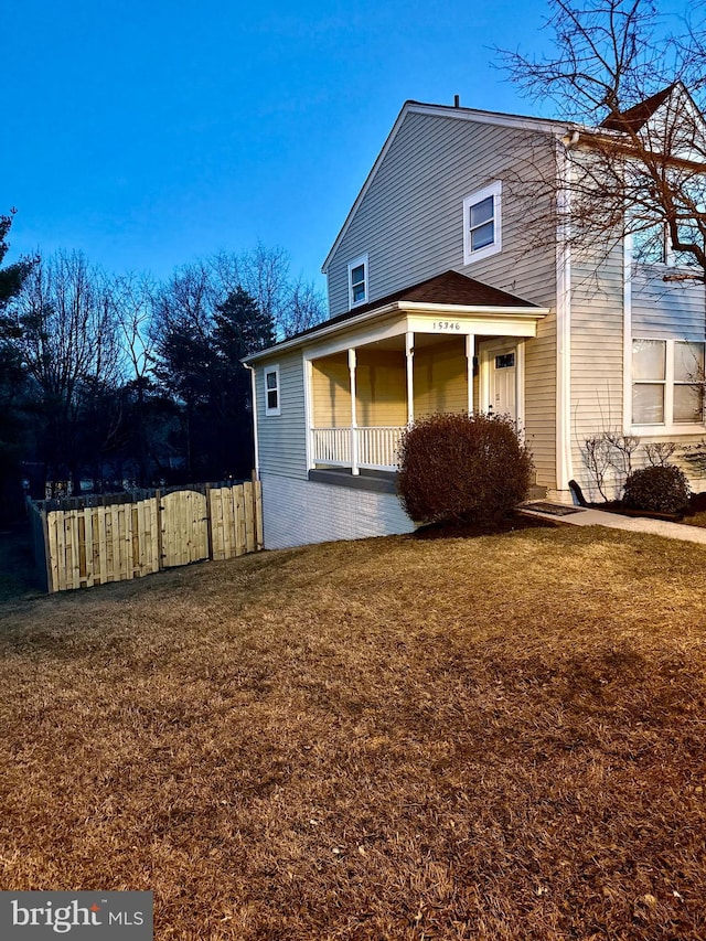 back of property with a porch, a lawn, and fence