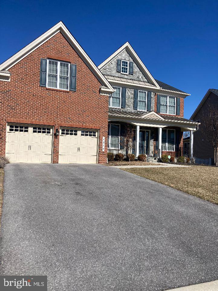 view of front of property with a porch, brick siding, an attached garage, and aphalt driveway